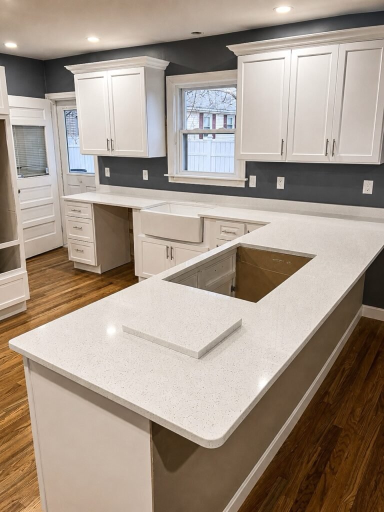 White quartz countertops with a farmhouse sink and white cabinetry